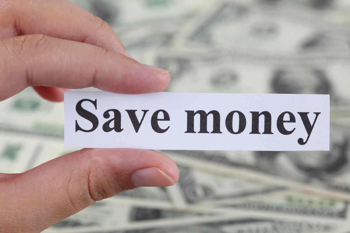 A woman's hand holding a paper with save money wording.