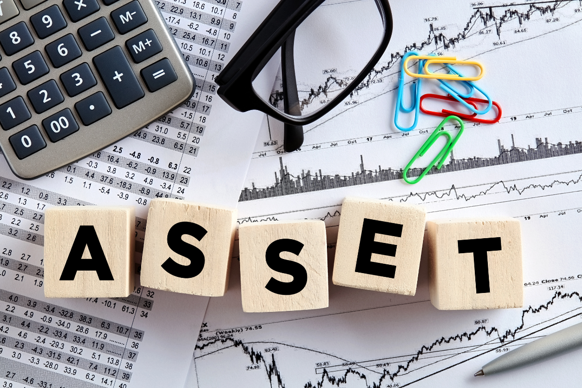 The image tells about a calculator, pins, an eyeglass, papers with graphs, and wooden cubes with letters referring to protecting my assets and wealth to keep you financially secure in the future.