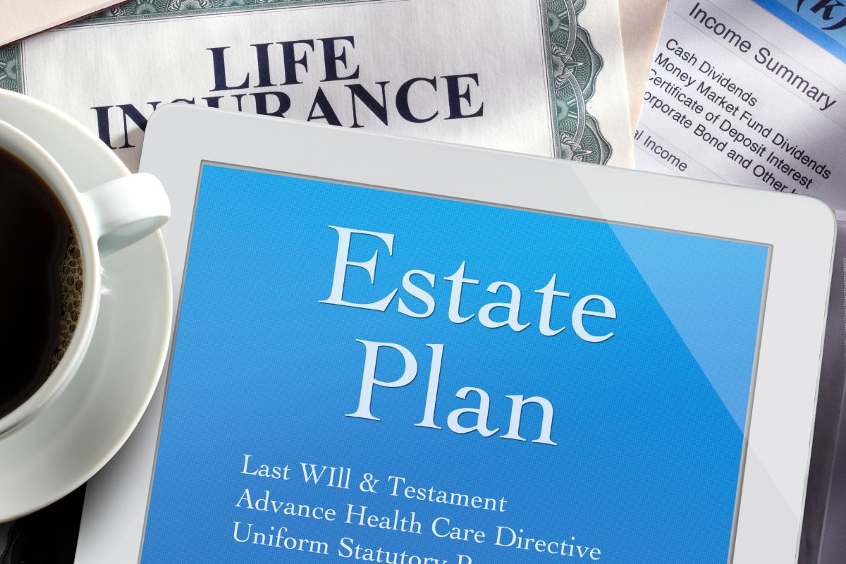 The picture tells about papers with notes, a coffee, and a tablet device with a screen display which means steps to start estate planning and gives you control over what happens to your stuff.