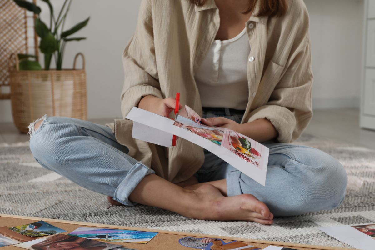The photo shows a woman creating a vision board.