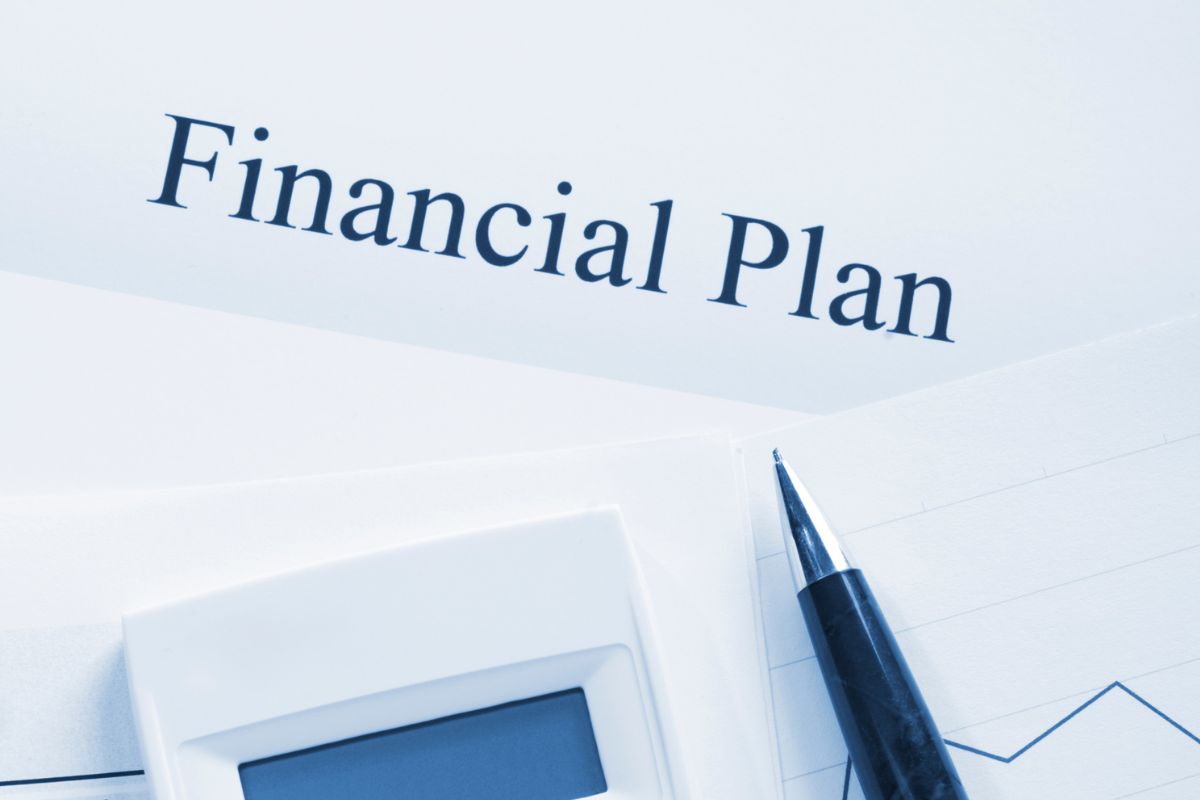 The photo shows a pen, a calculator, and papers with notes which refer to reviewing and adjusting financial plans regularly to keep you focused and flexible.