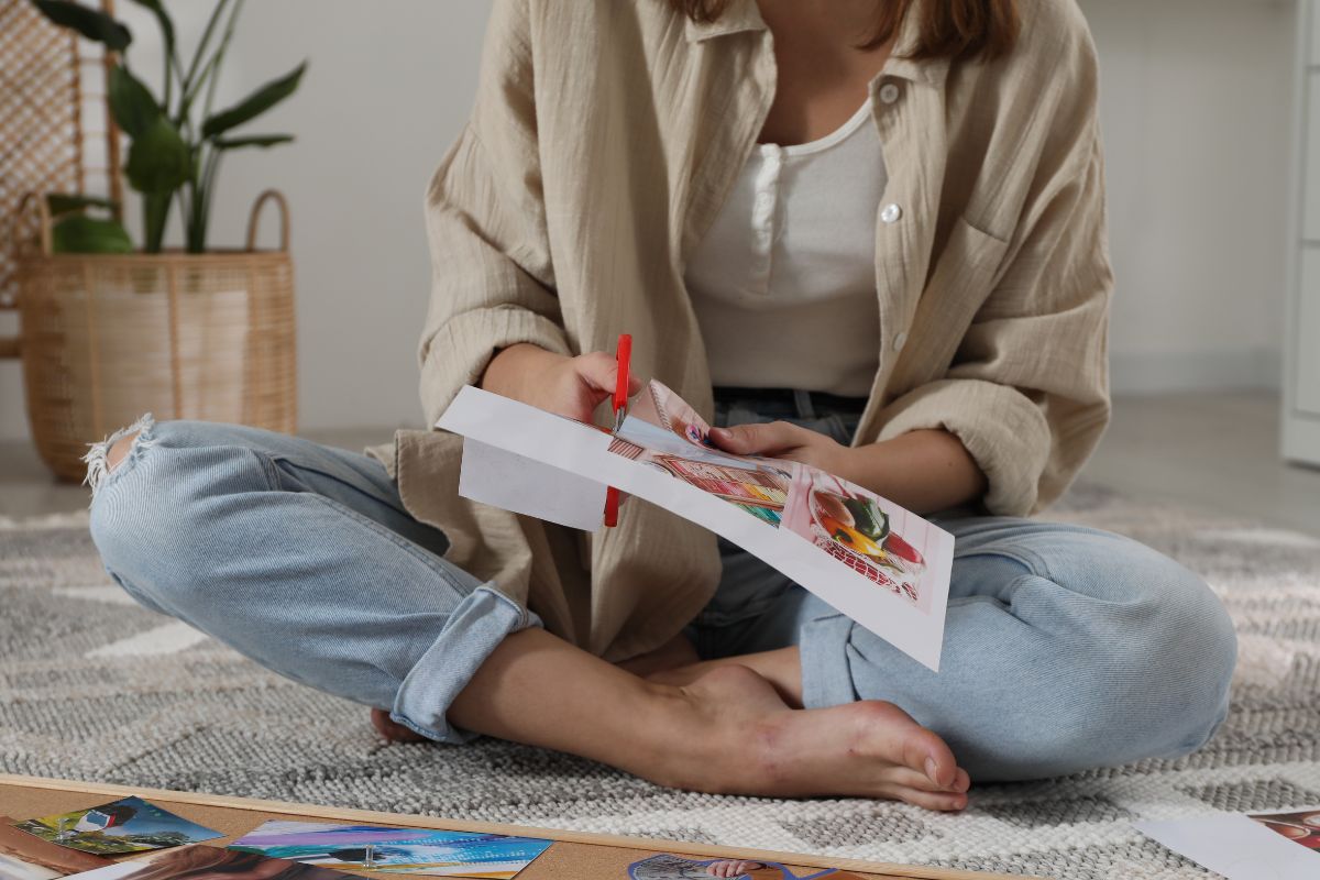 The photo shows a lady creating a money vision board.