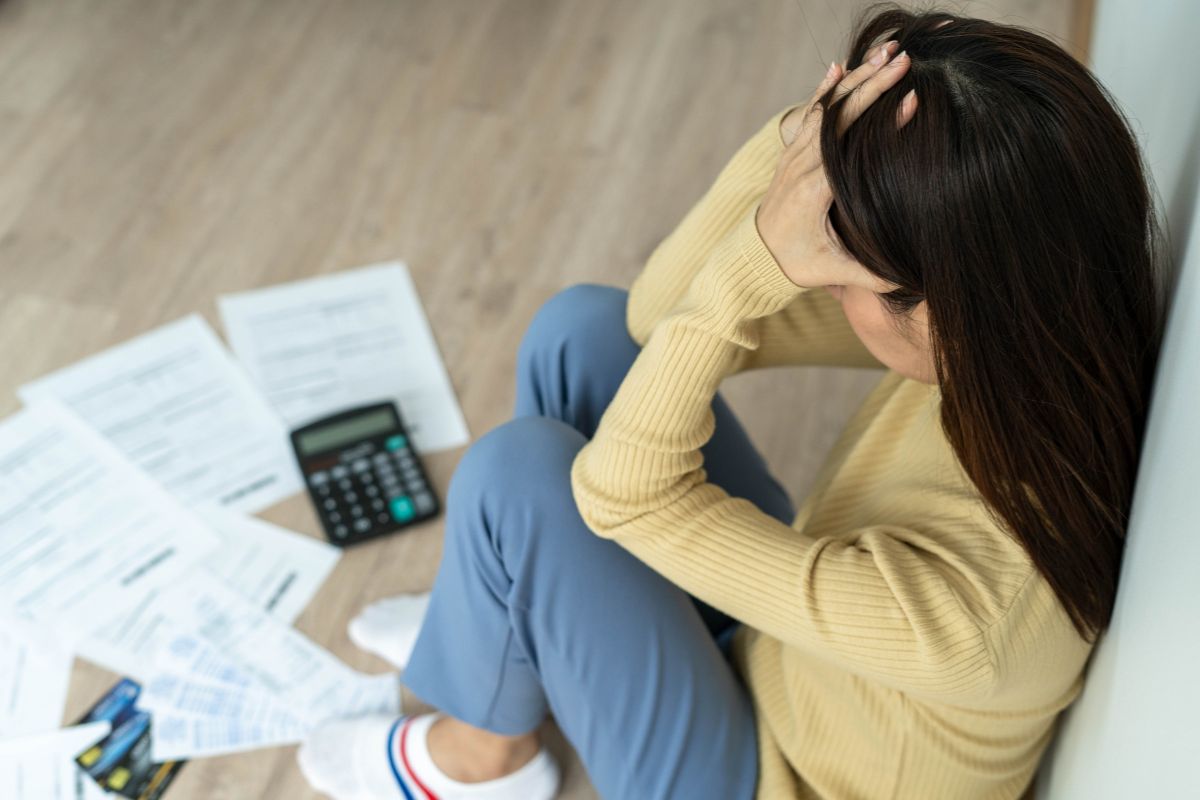 The photo shows papers on the floor, a calculator, credit cards, and a frustrated girl sitting on the floor which means using financial mistakes is one of the best ways to turn failure into something useful.