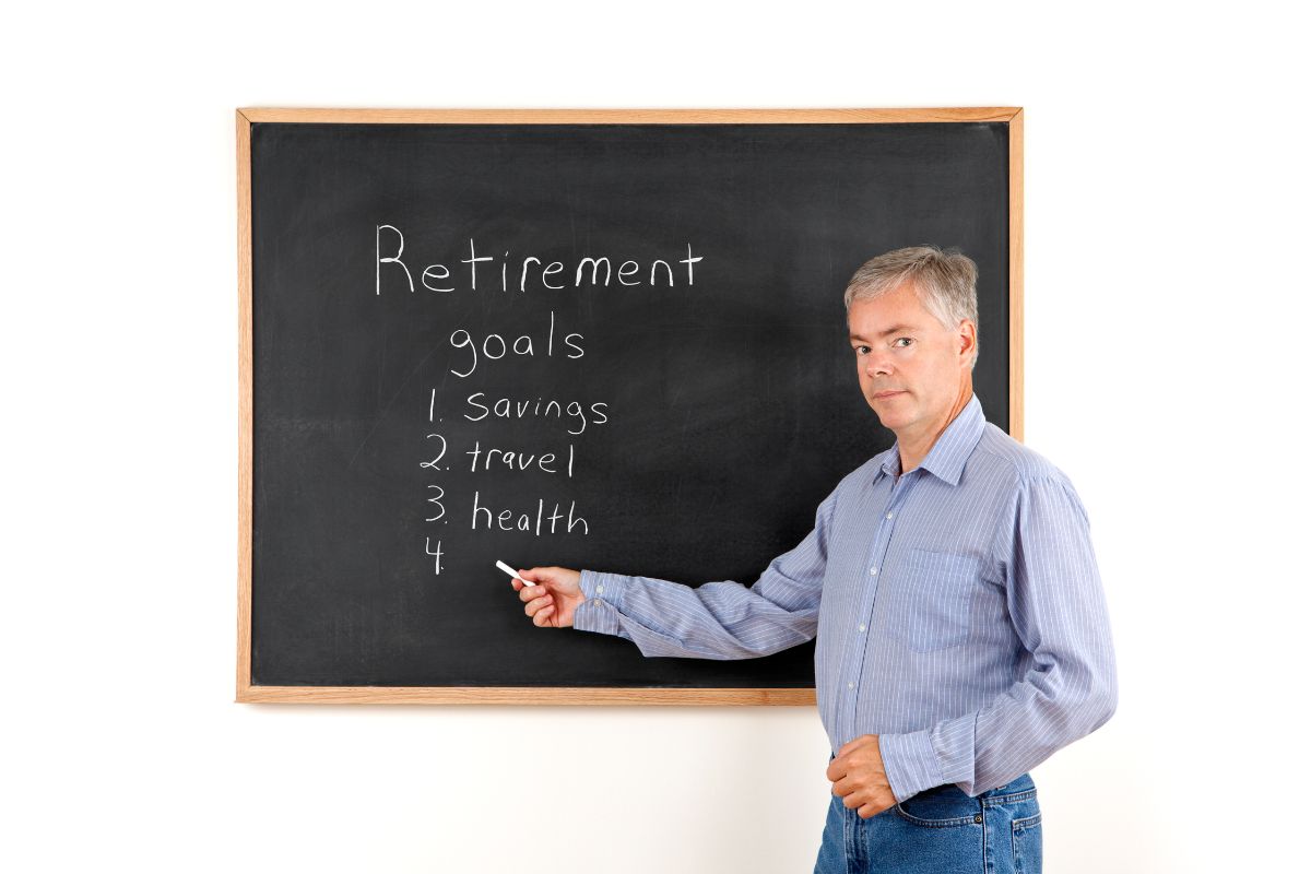 The photo shows a board with notes and a senior man holding a chalk indicating to set retirement goals makes it easier to know how much to save.