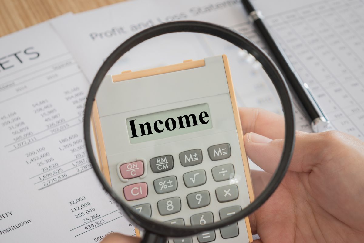 The picture is about a man's hand holding a calculator with income wording.