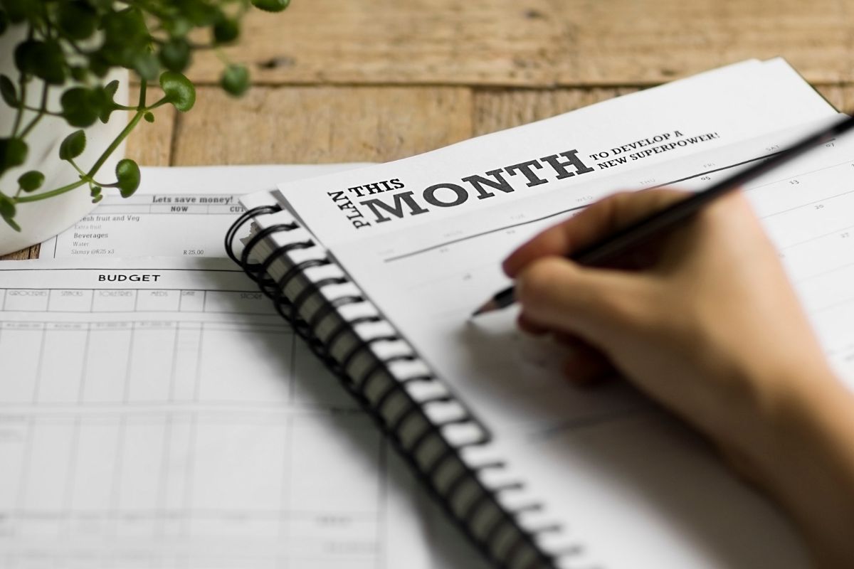The photo shows a lady's hand making a budget planner.