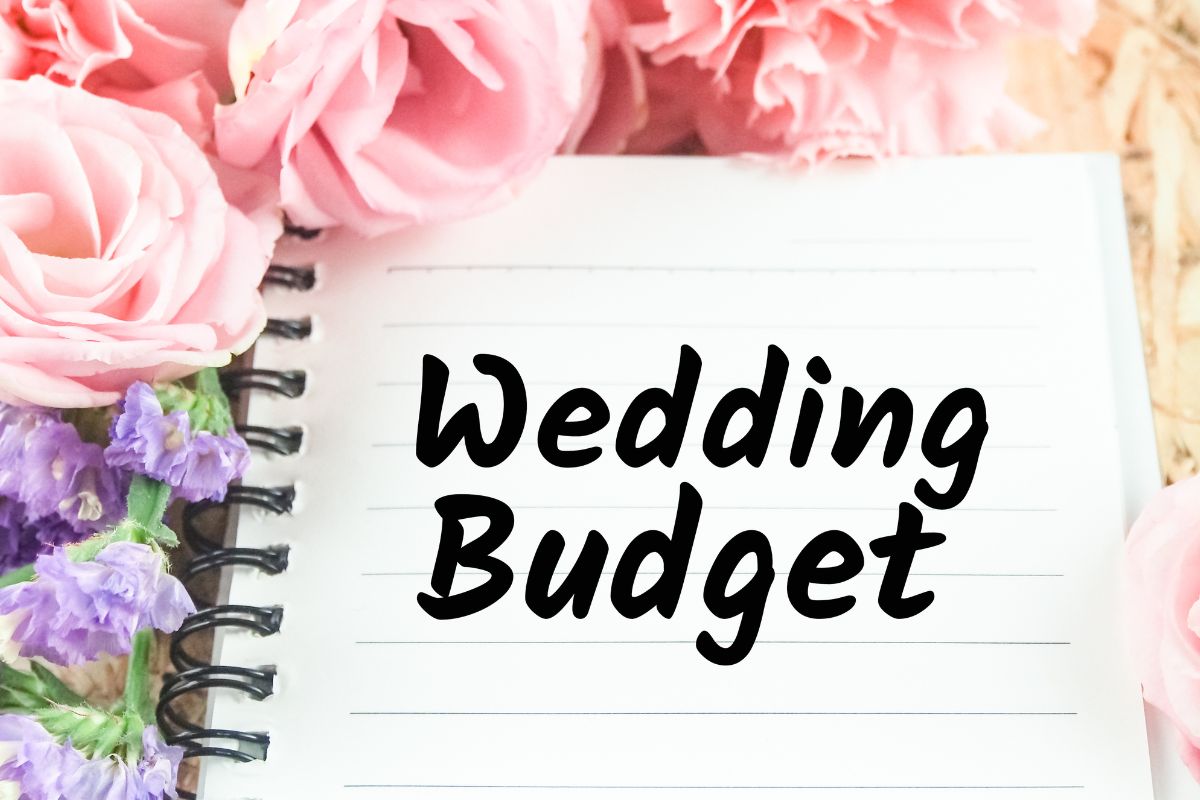 The image shows flowers and paper with wedding budget wording.