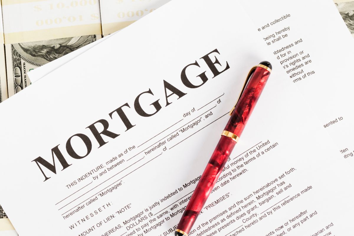 The photo shows a dollar bill and a paper with mortgage wording.