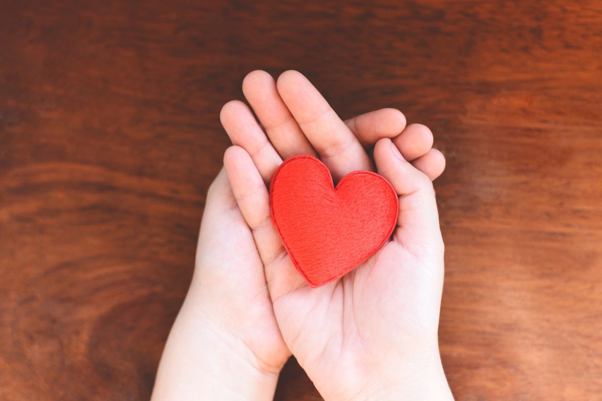 The image shows a girl's hand holding a heart shape.