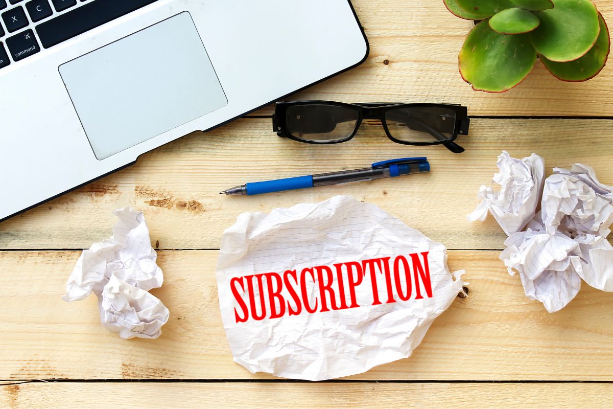 The photo of a laptop and a paper with subscription wording.
