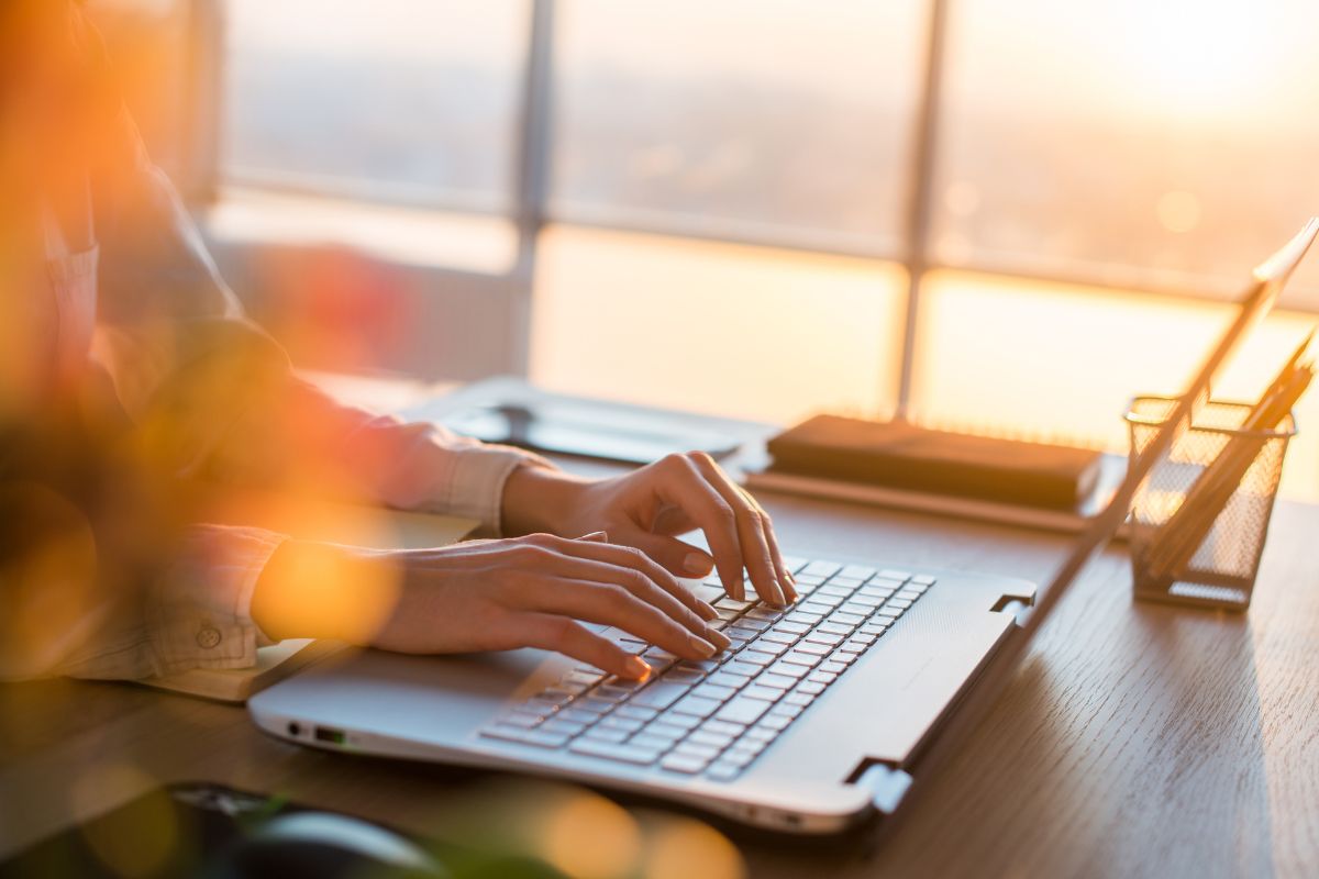 The image is about a woman's hand using a laptop for an income tracker.