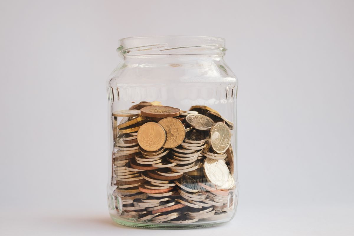 The image is about a jar of wine filled with coins.