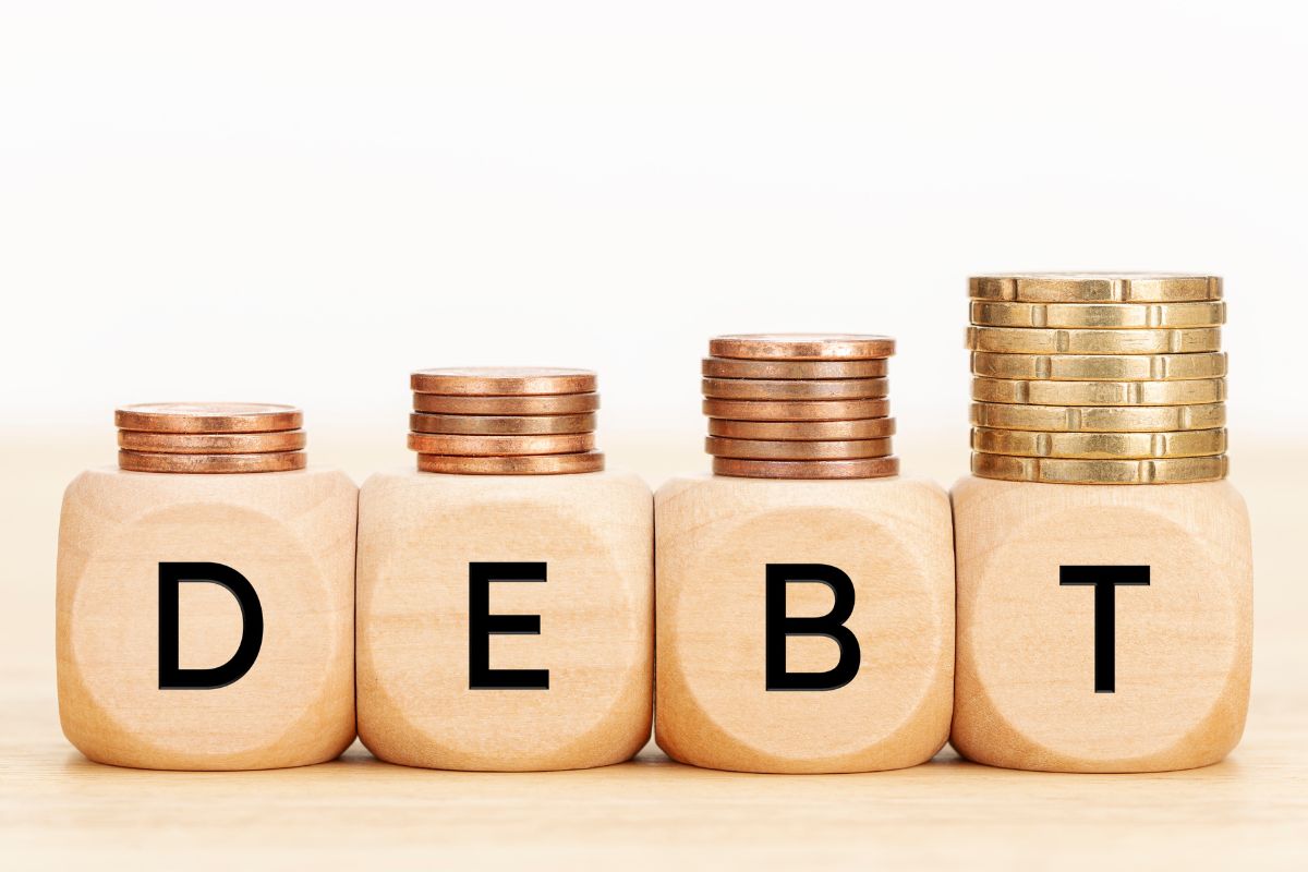 The photo shows coins and debt wording.