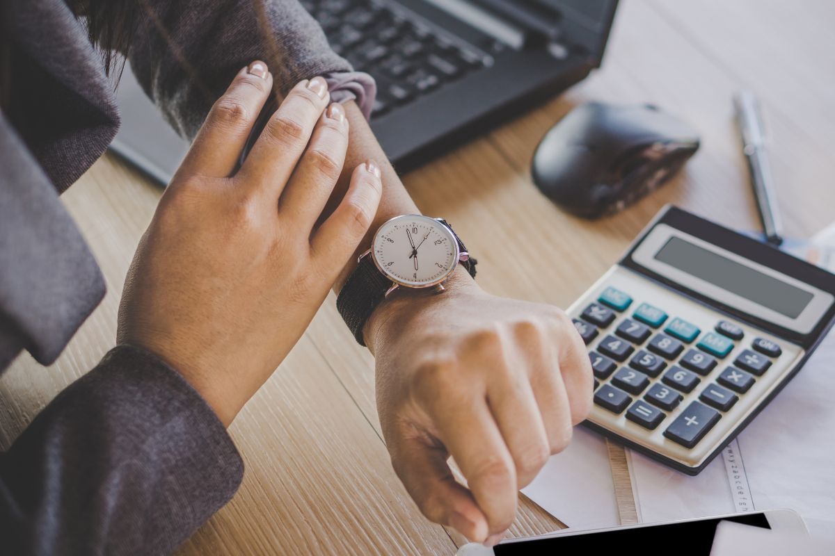 The image shows a woman's hand checking her watch.