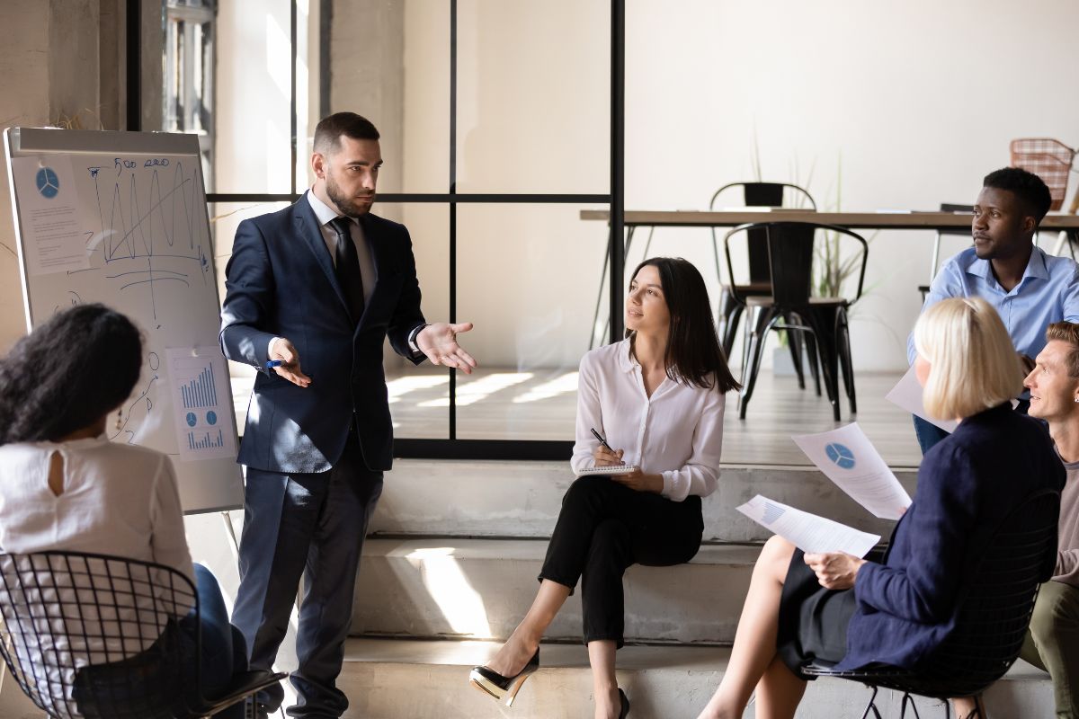 The image shows a man talking to his colleagues.