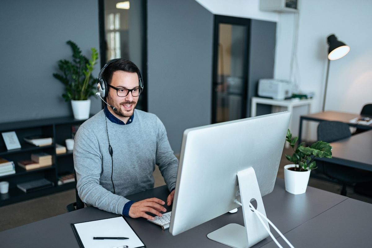 The image shows a man working as an IT support specialist.