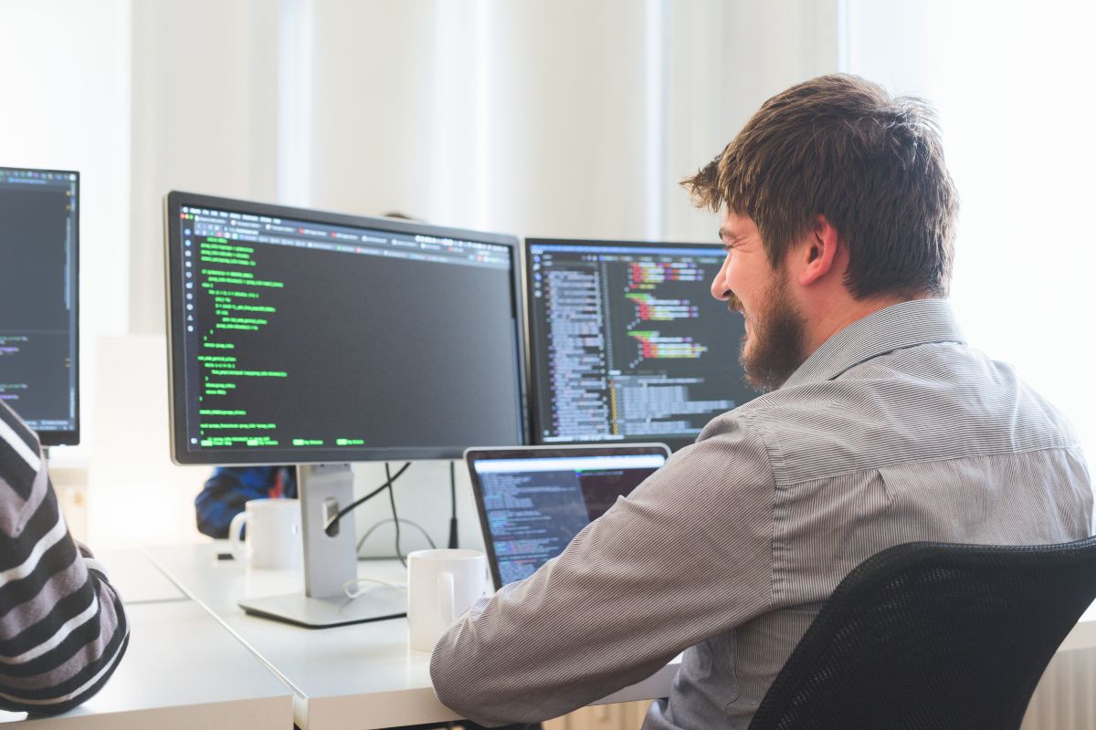The photo is of a man using a laptop as a web developer.