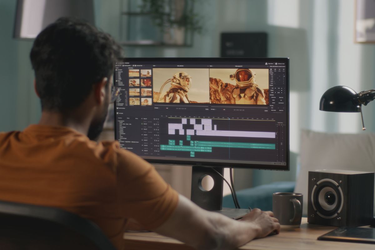 The photo is of a man using a computer for video editing.