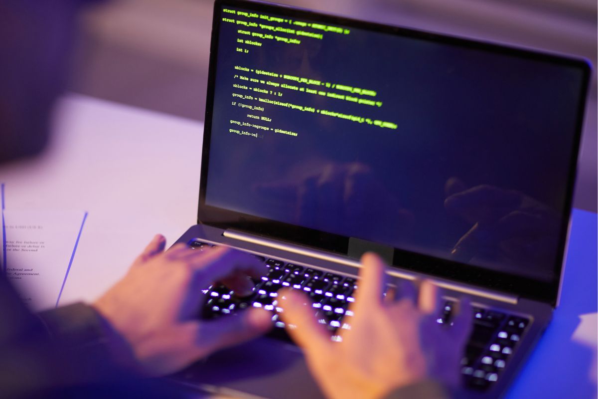 The picture of a man coding on his laptop.