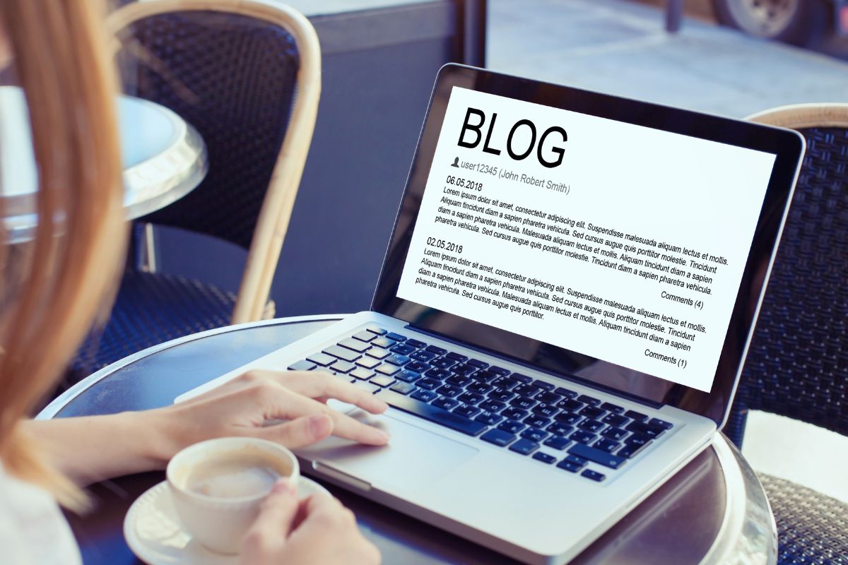 The photo shows a woman blogging using a laptop.