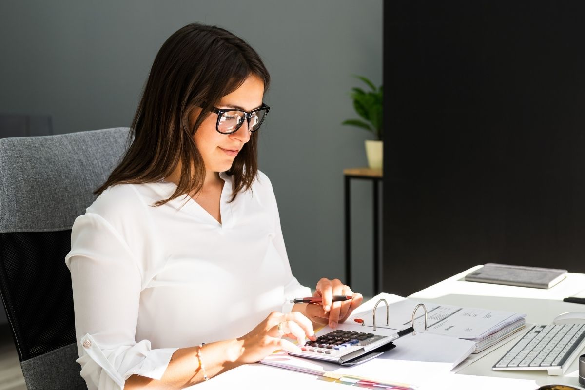 The image is about a woman using a calculator for bookkeeping.