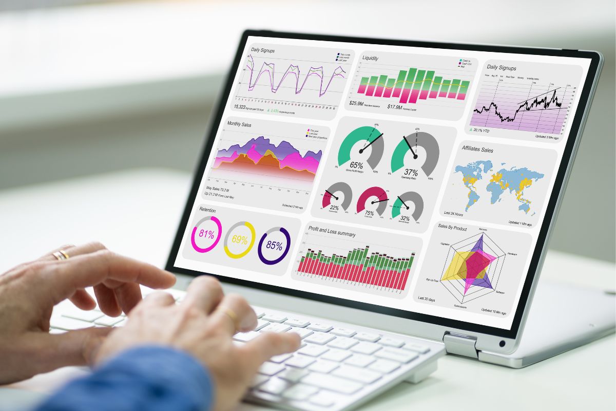 The image shows a man's hand using the laptop for data analysis.