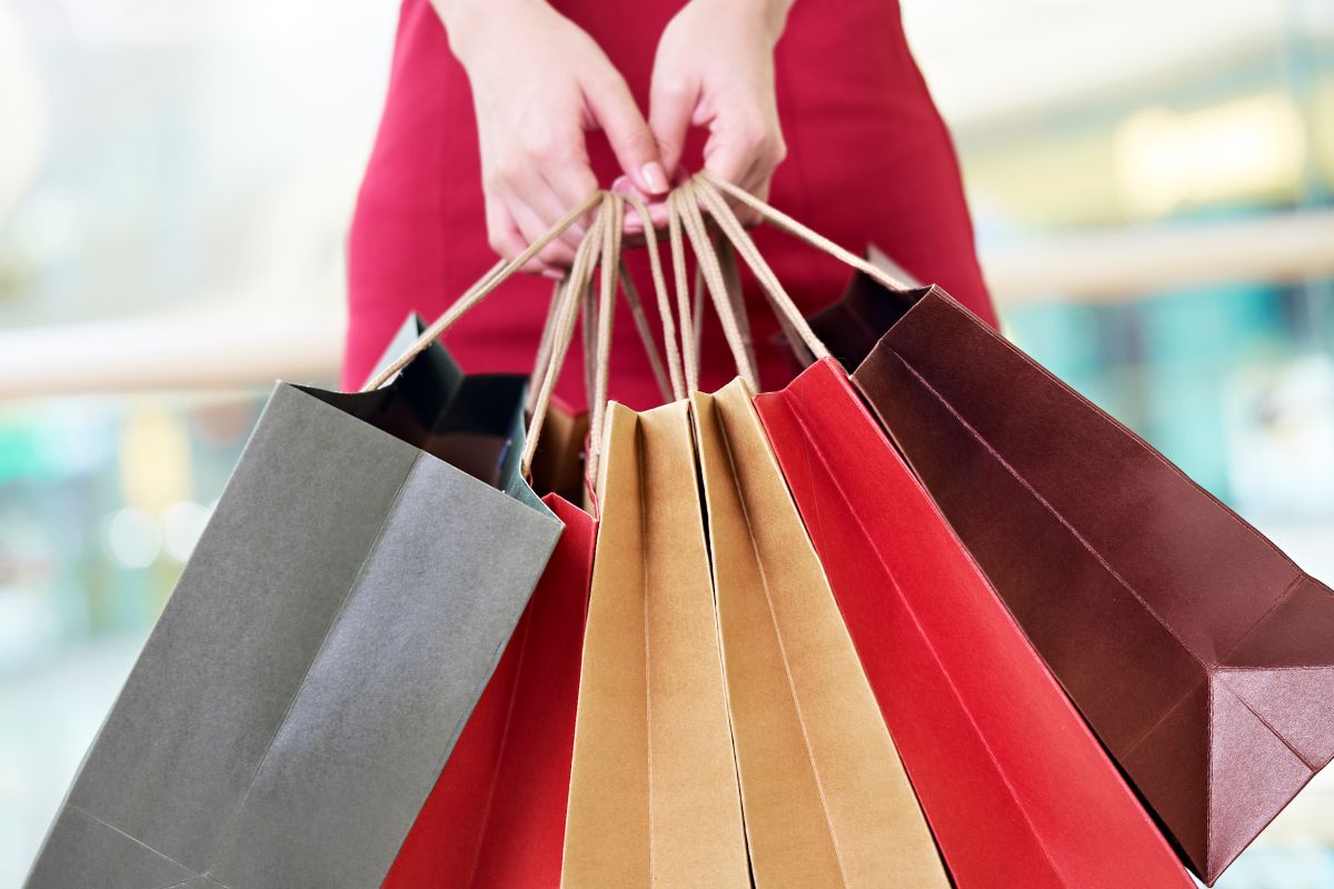 The photo is about a woman's hand carrying shopping bags with a lifestyle creep.