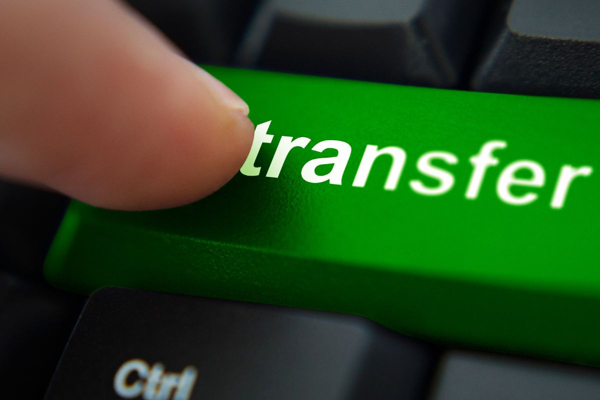 The image shows a man's hand setting up an automatic transfer.