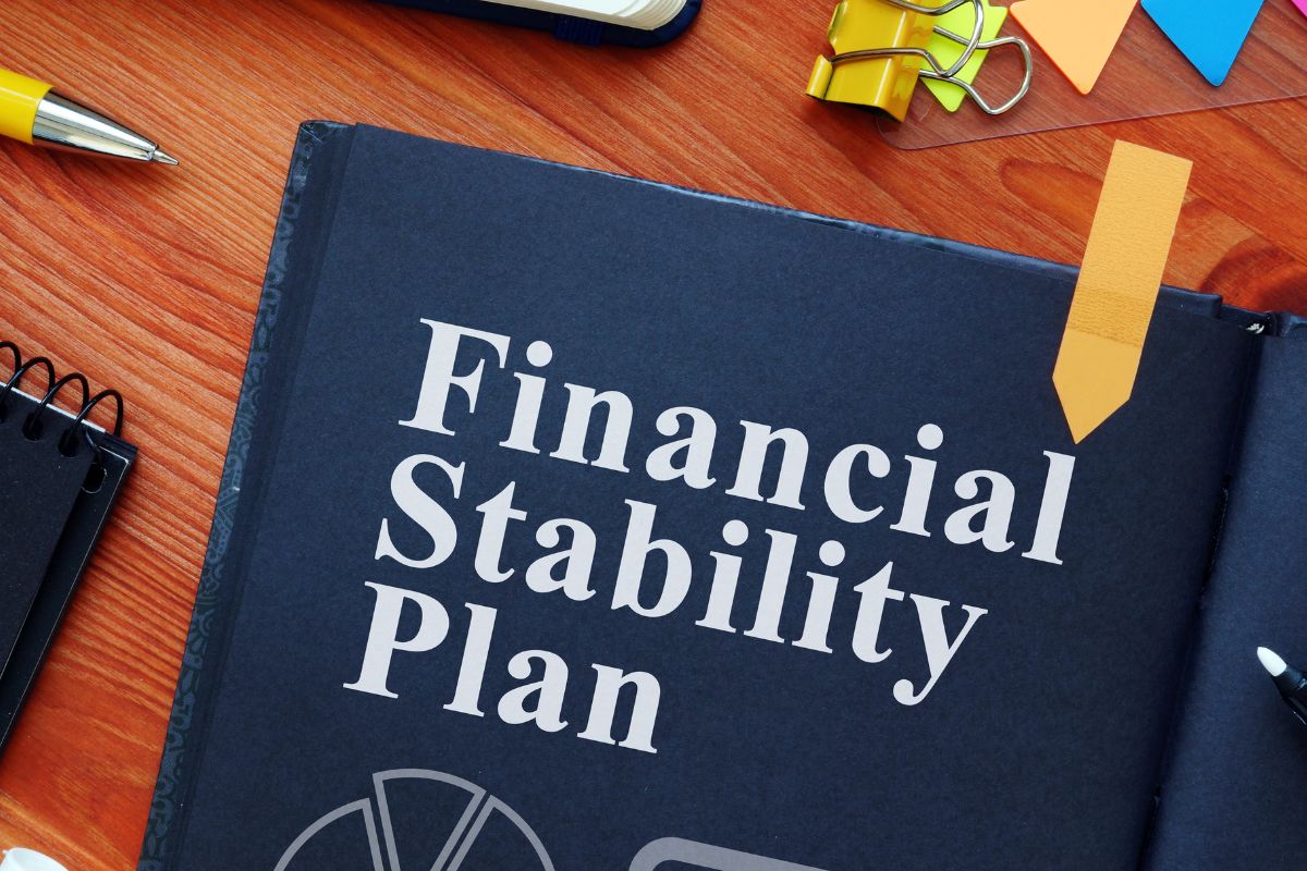 The photo shows a black notebook with financial stability plan wording.