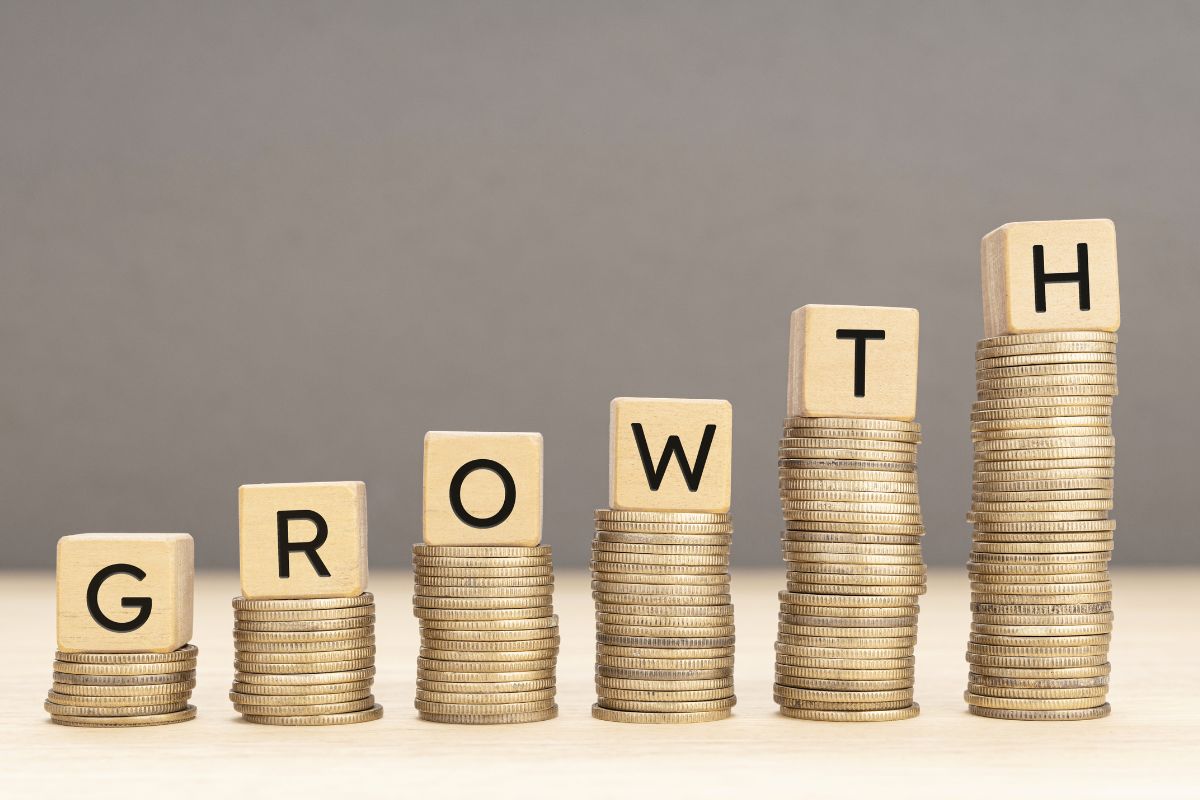 The image shows a stack of coins and growth wording.