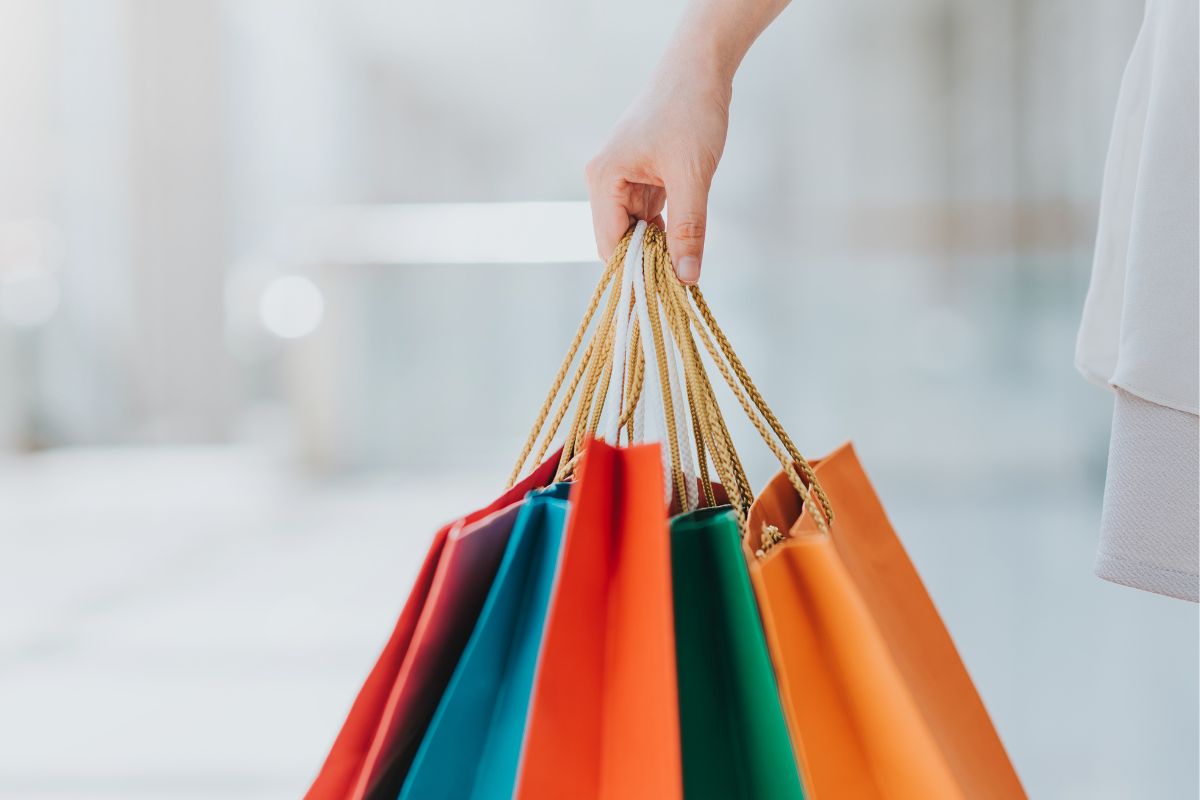 The image shows a woman's hand carrying shopping bags.