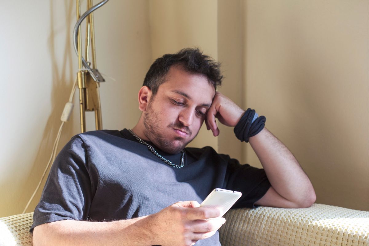The photo shows a man wasting time on the phone.