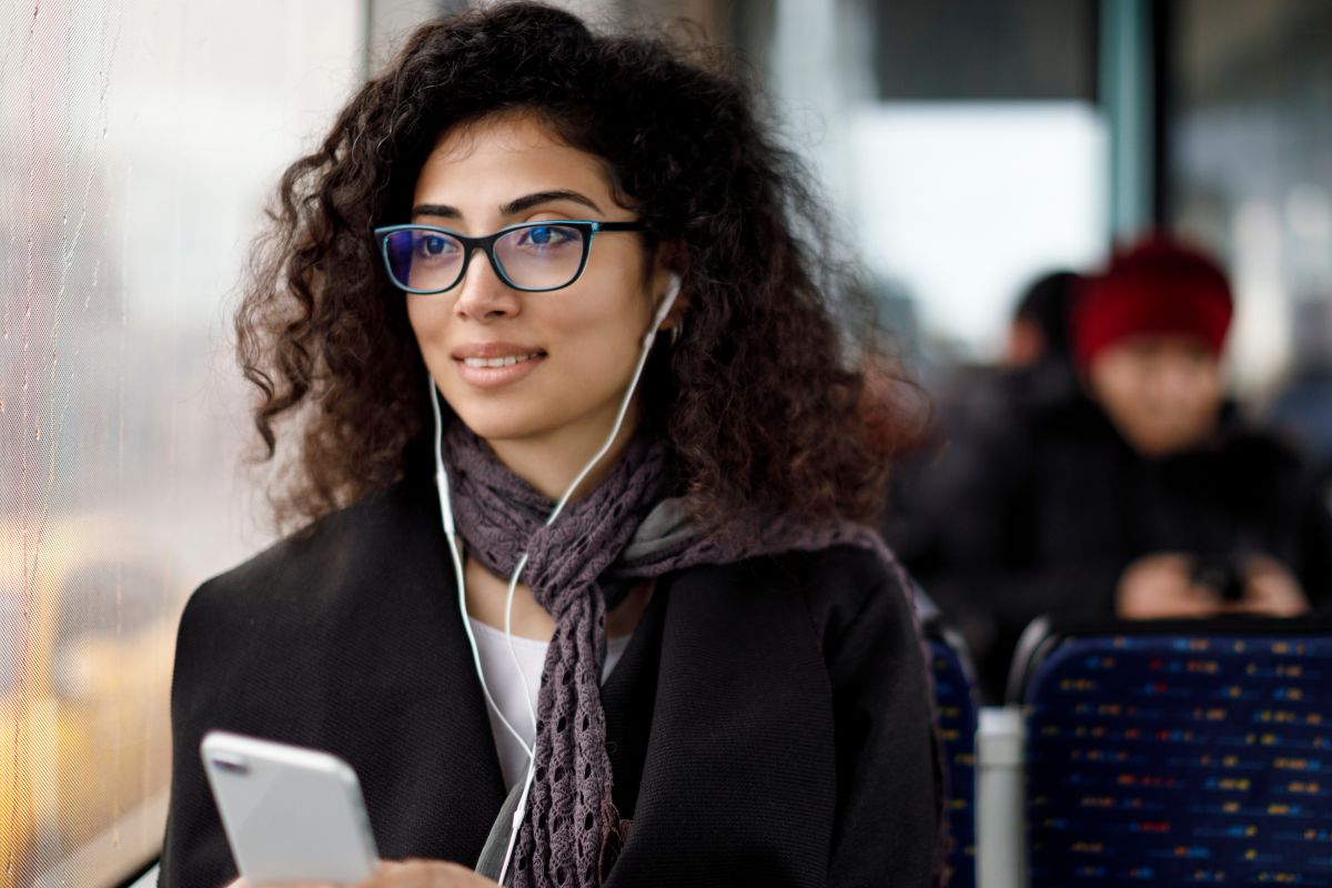 The image shows a young lady listening to financial podcasts.