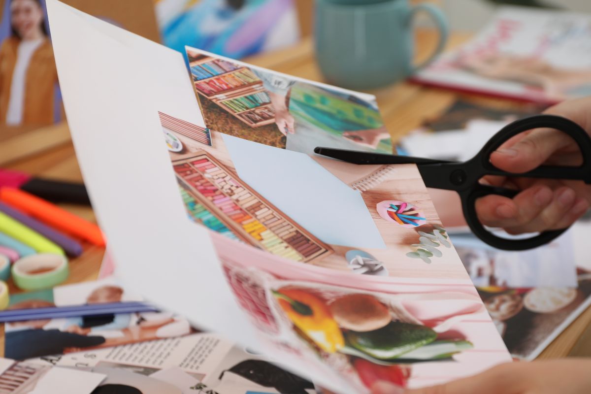 The photo shows a woman's hand cutting a magazine for a money goals picture.