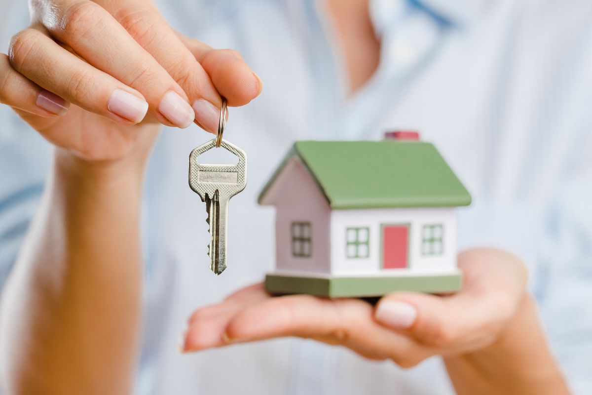 The image shows a lady's hand holding a paid-off house.
