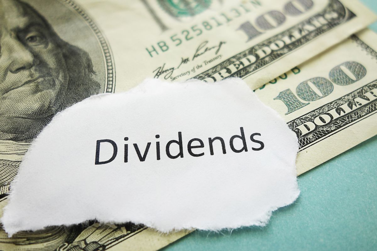 The photo shows dollar bills and a paper with dividends wording.