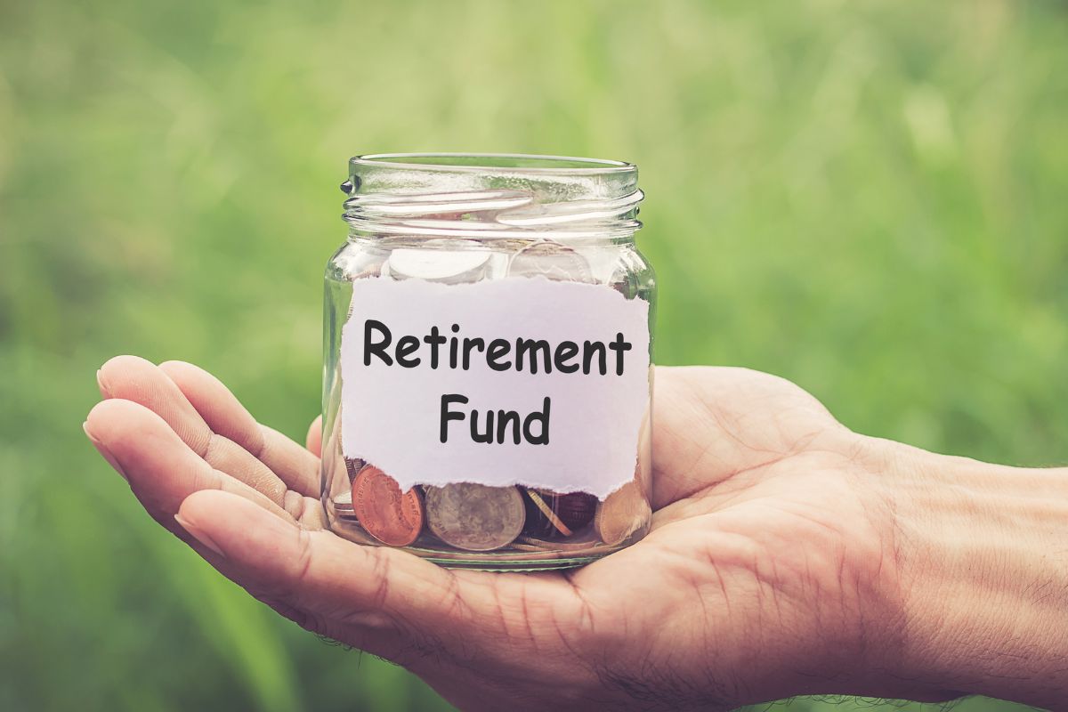 The photo shows a man's hand holding a jar with coins and a retirement fund note.