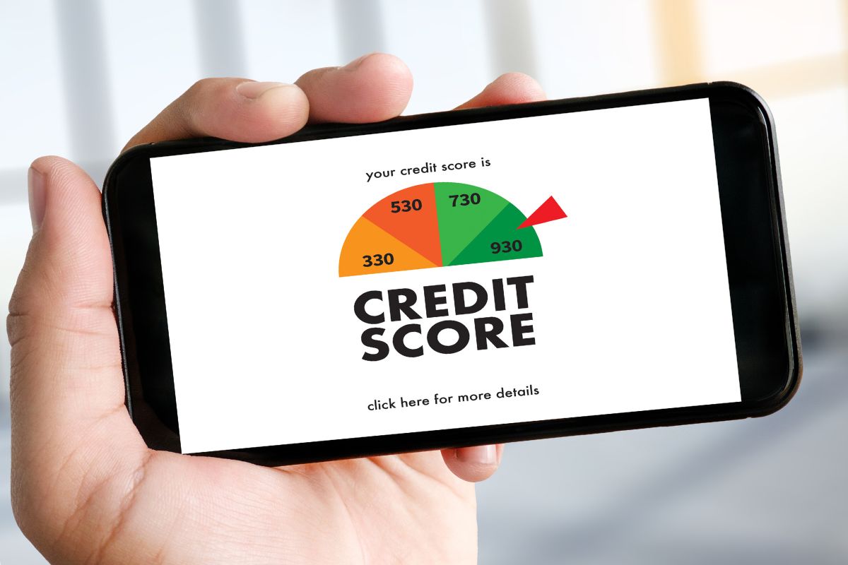 The image shows a man's hand holding a phone with a credit score screen display.