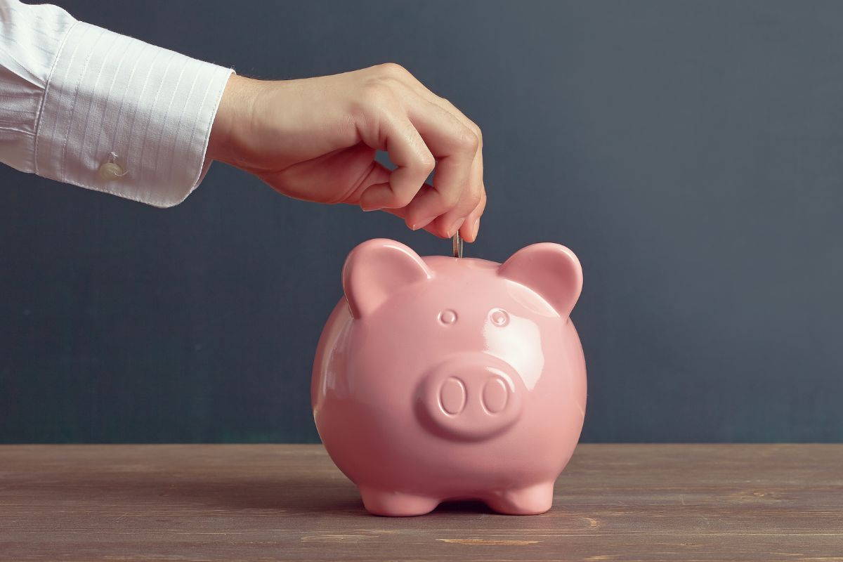 The image shows a man's hand saving money.