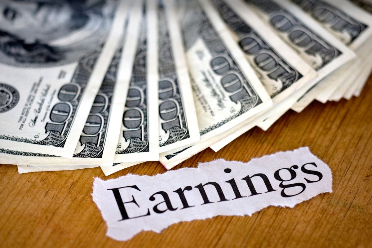 The picture shows dollar bills and a piece of paper with an earning note.