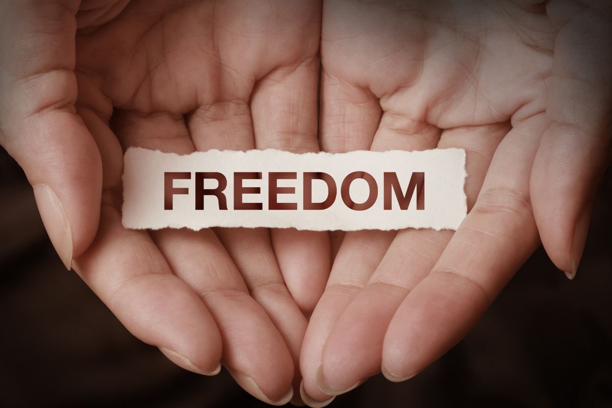 The image shows a woman's hand holding a paper with freedom wording.