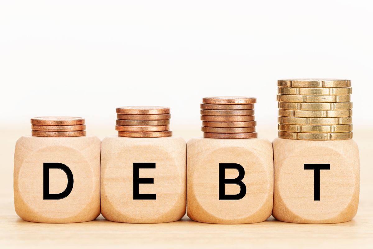 The image of stacked coins and wooden cubes with debt combined.