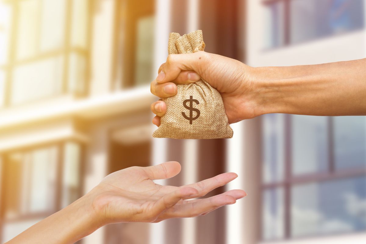 The picture shows a man's hand lending money to the lady's hand.