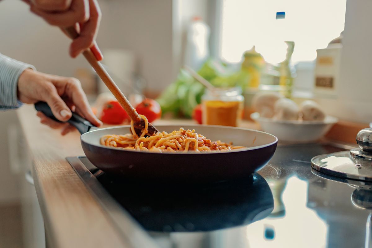 The picture shows a woman cooking a meal at home.