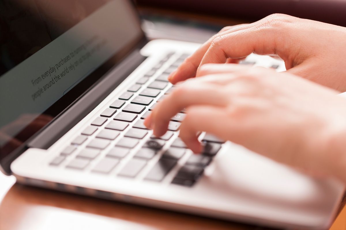 The picture of a woman's hand typing on a laptop as a data entry clerk.