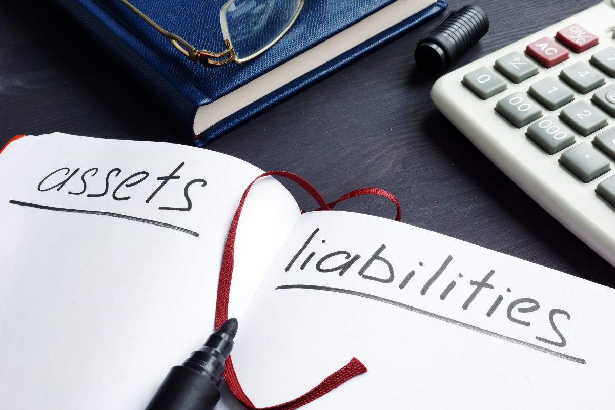 The image shows a notebook with the wording of liabilities vs assets.
