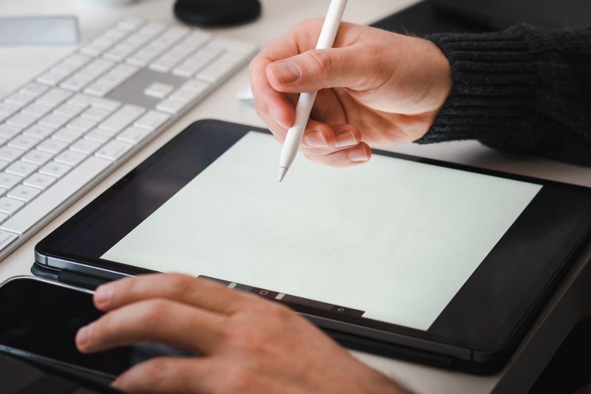 An image of an iPad, with a stylus on someone's hands. 