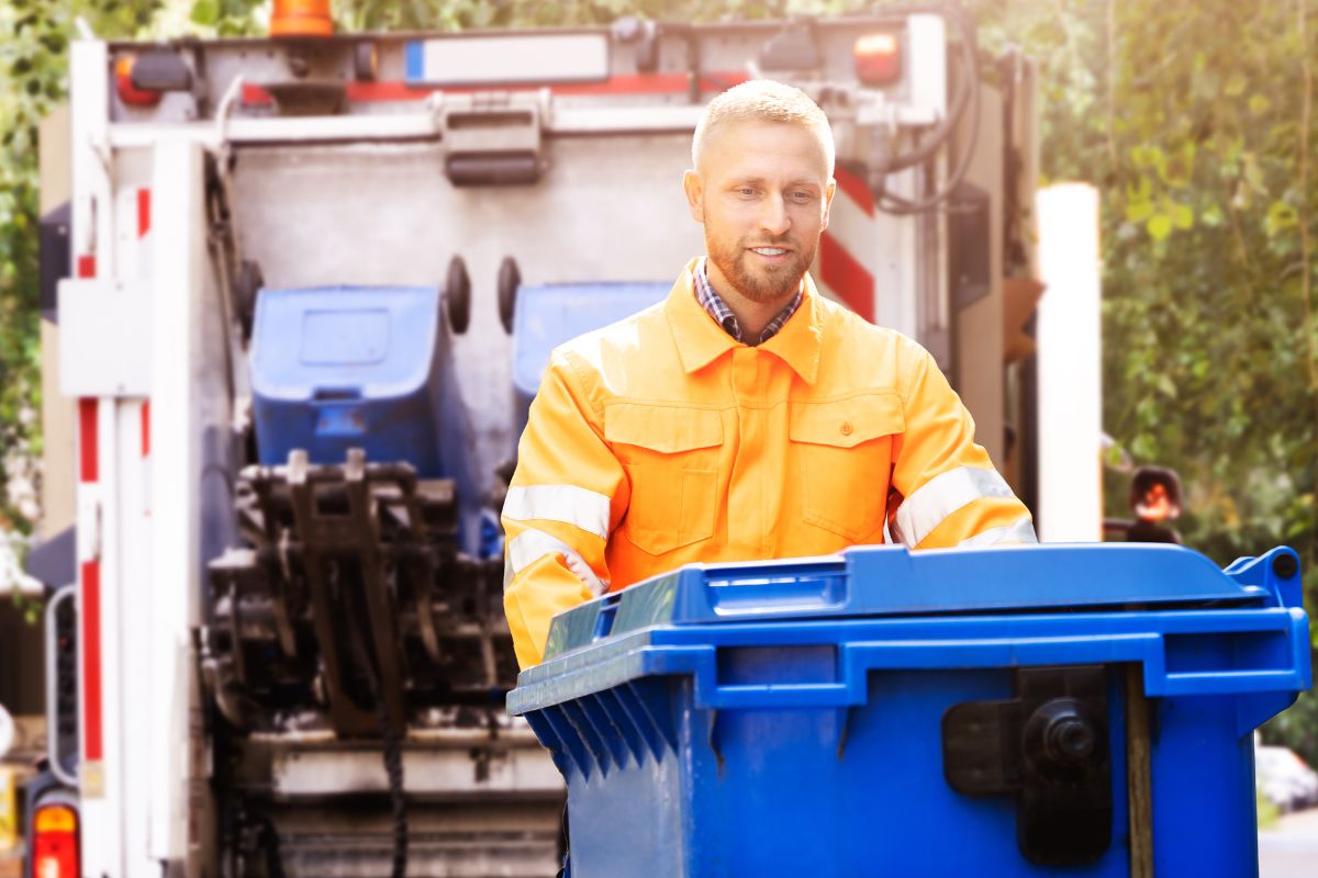 A man cleaning out a garbage can.