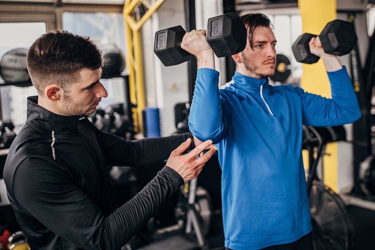 A personal trainer with his weightlifting student.