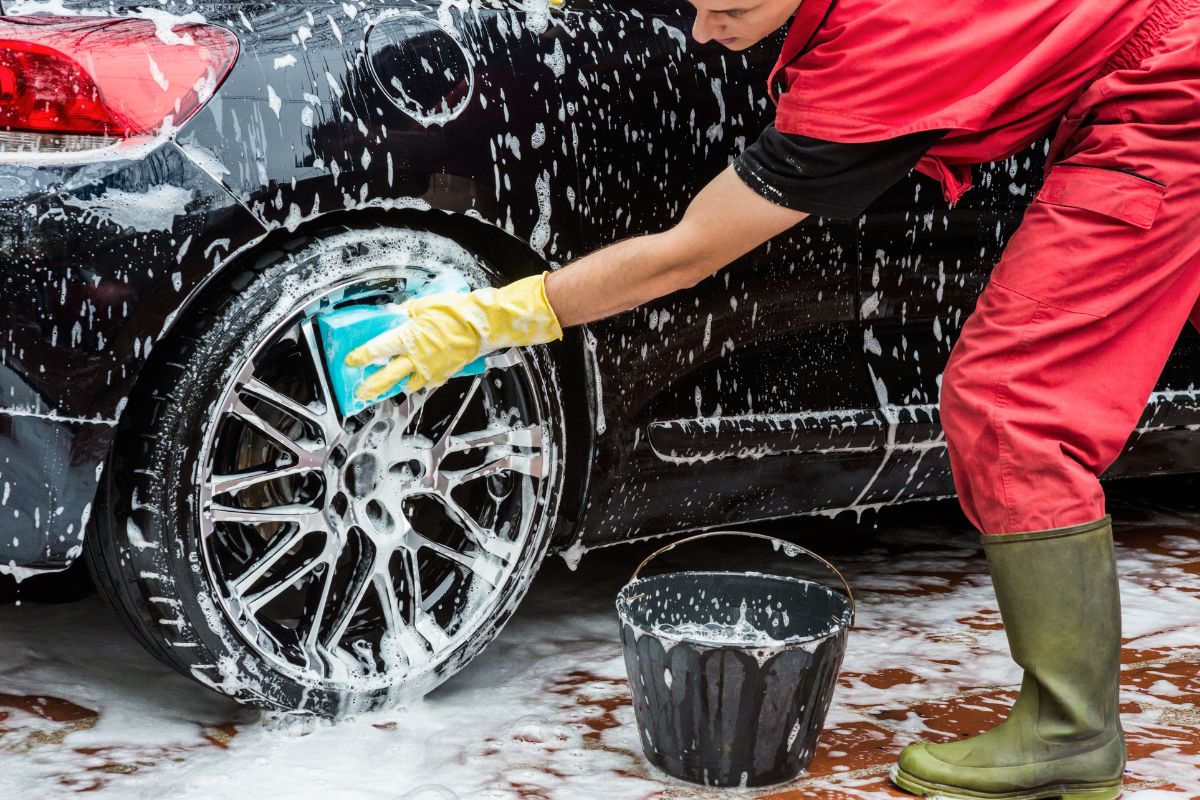 A picture of a man washing a car.